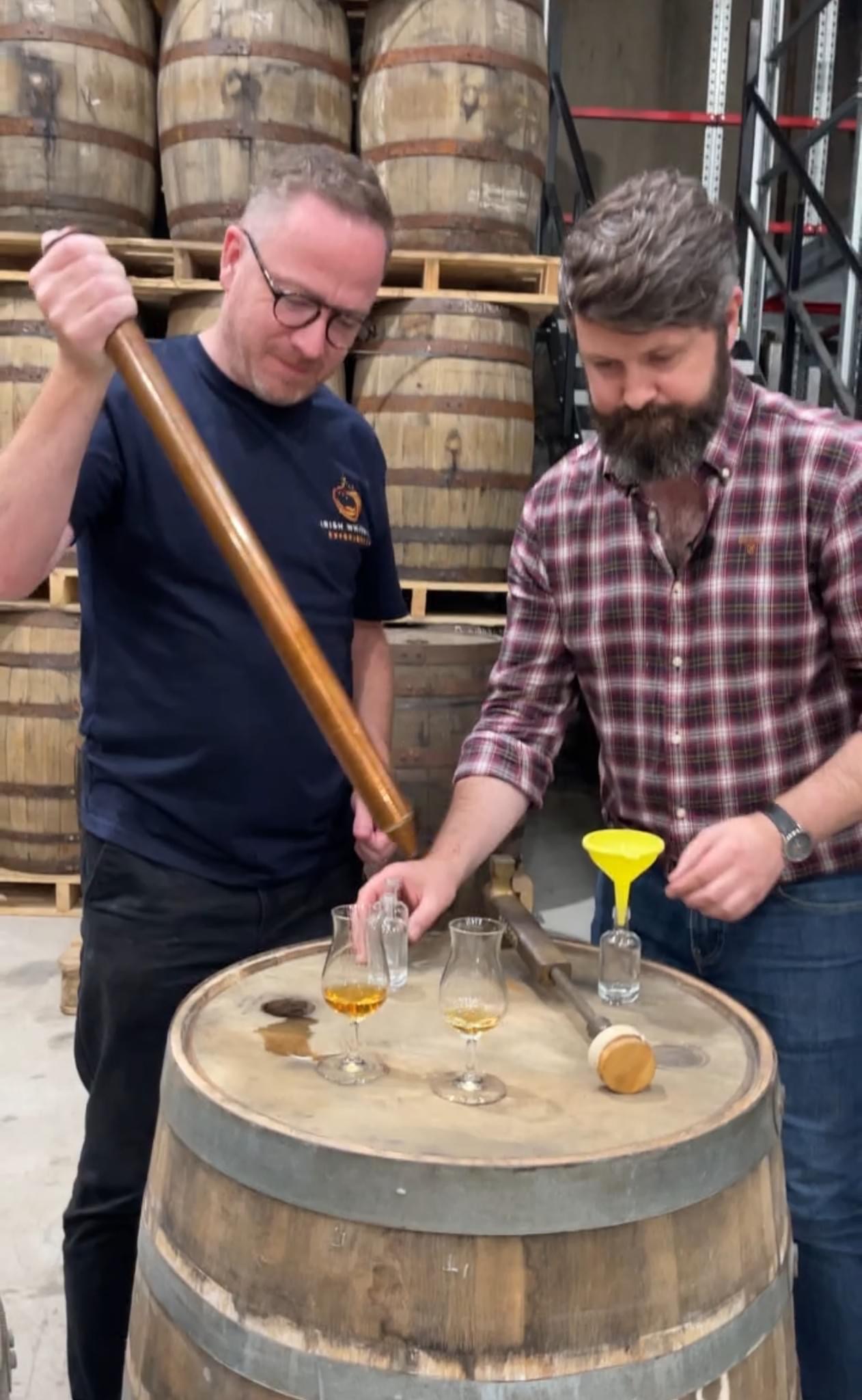 Barry Chandler drawing whiskey from a cask during a warehouse visit